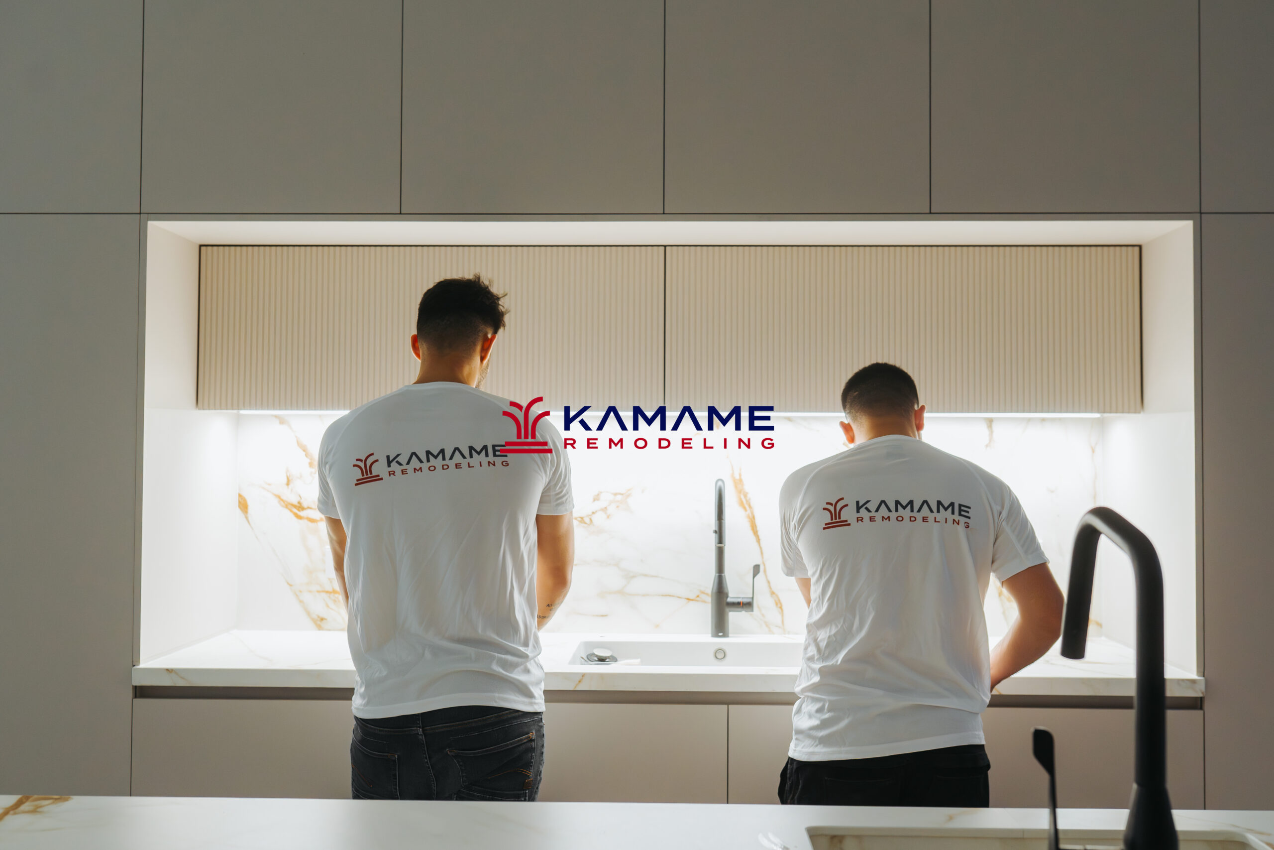 Two construction workers installing new cabinetry and countertops as part of a kitchen remodel, with tools and materials spread across the work area.