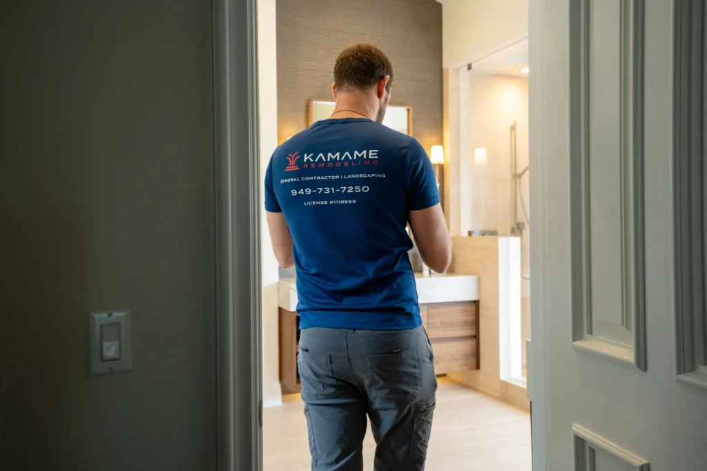 Kamame Remodeling team member in a branded shirt walking into a finished bathroom